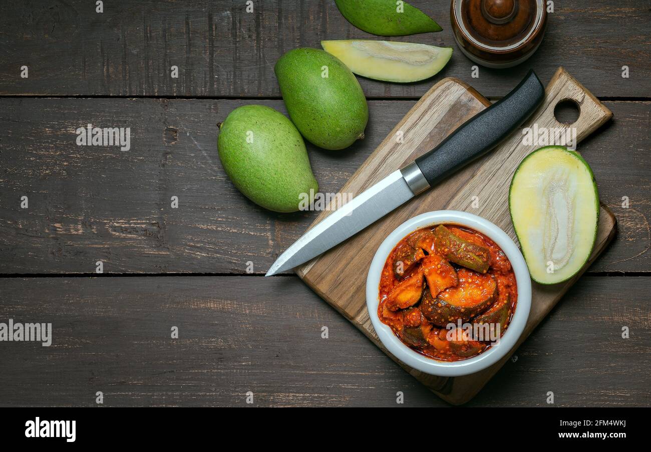 Rohe Mangobeize oder aam ka aachar oder achar in Eine weiße Schale und auf einem hölzernen Hintergrund Thema mit Mangos Stockfoto