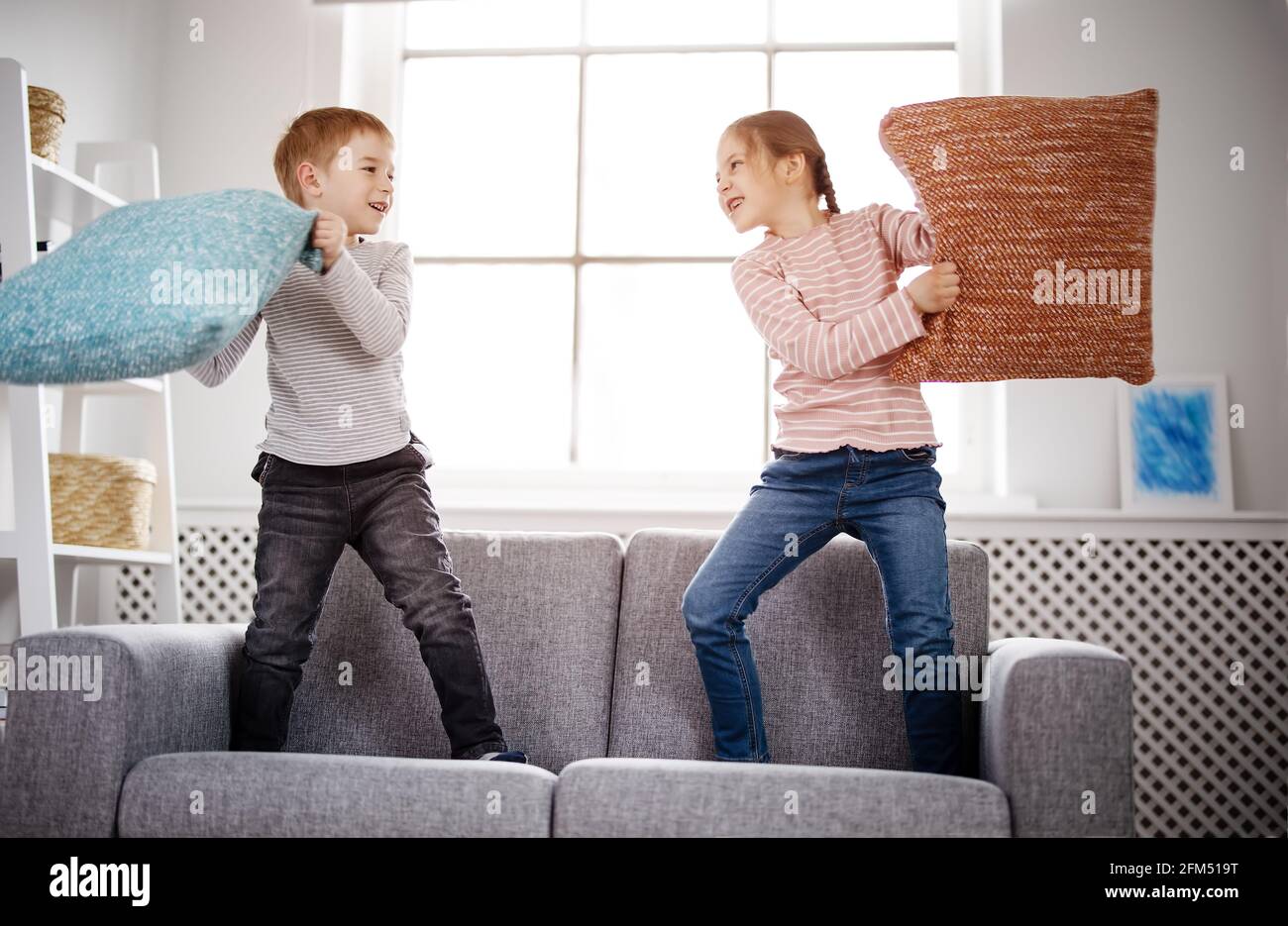 Niedliche Kinder kämpfen mit Kissen auf dem Sofa Stockfoto