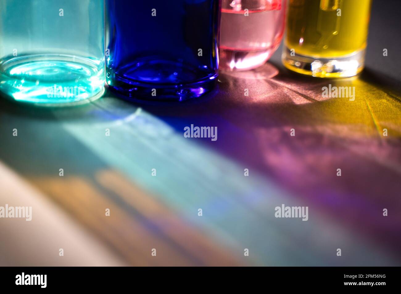 Blau türkis rosa und gelbe Glasflaschen und Reflexionen in rauem Licht. Beauty-Produkte in einem neuen Licht. Stockfoto