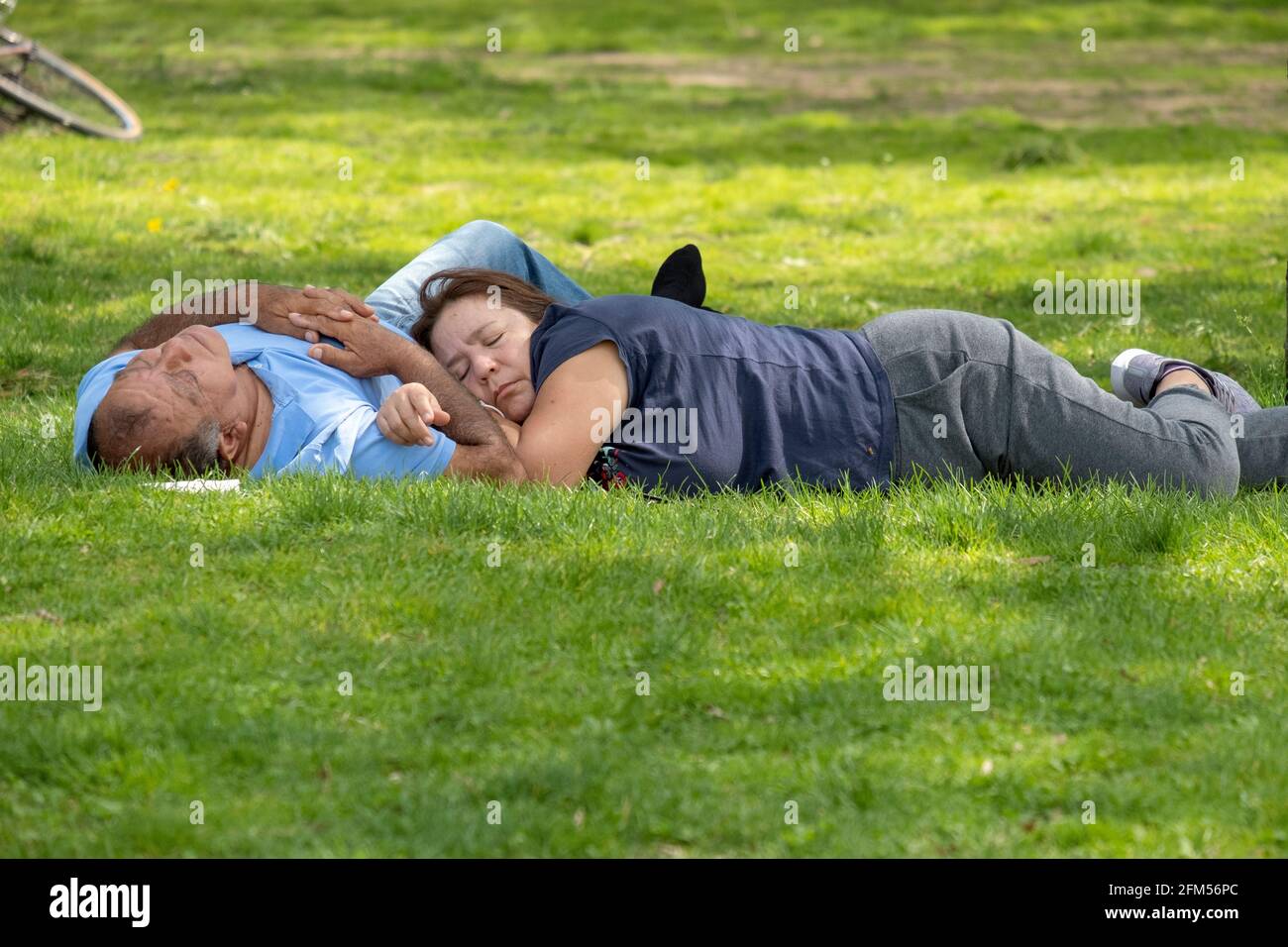 Ein Paar, vermutlich Ehemann und Ehefrau, macht ein Mittagsschlaf im Flushing Meadows Corona Park in Queens, New York City. Stockfoto