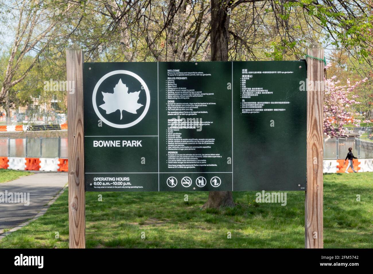 Ein dreisprachiges Schild am Rande des Bowne Park in Queens, das Vorschriften für Mensch und Hund erklärt. Stockfoto