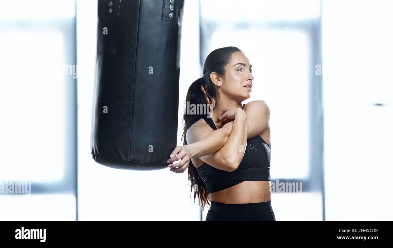 Junge Sportlerin, die sich in der Nähe des Boxsacks ausdehnt Stockfoto
