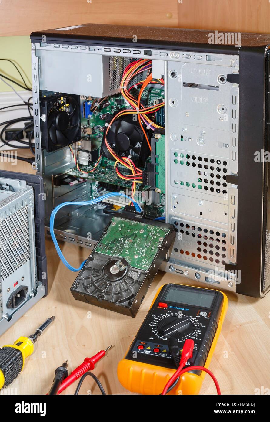 Reparieren oder Aktualisieren eines Computers. Tower-PC mit offener Seite und entfernter Festplatte. Niederlassung in Großbritannien Stockfoto
