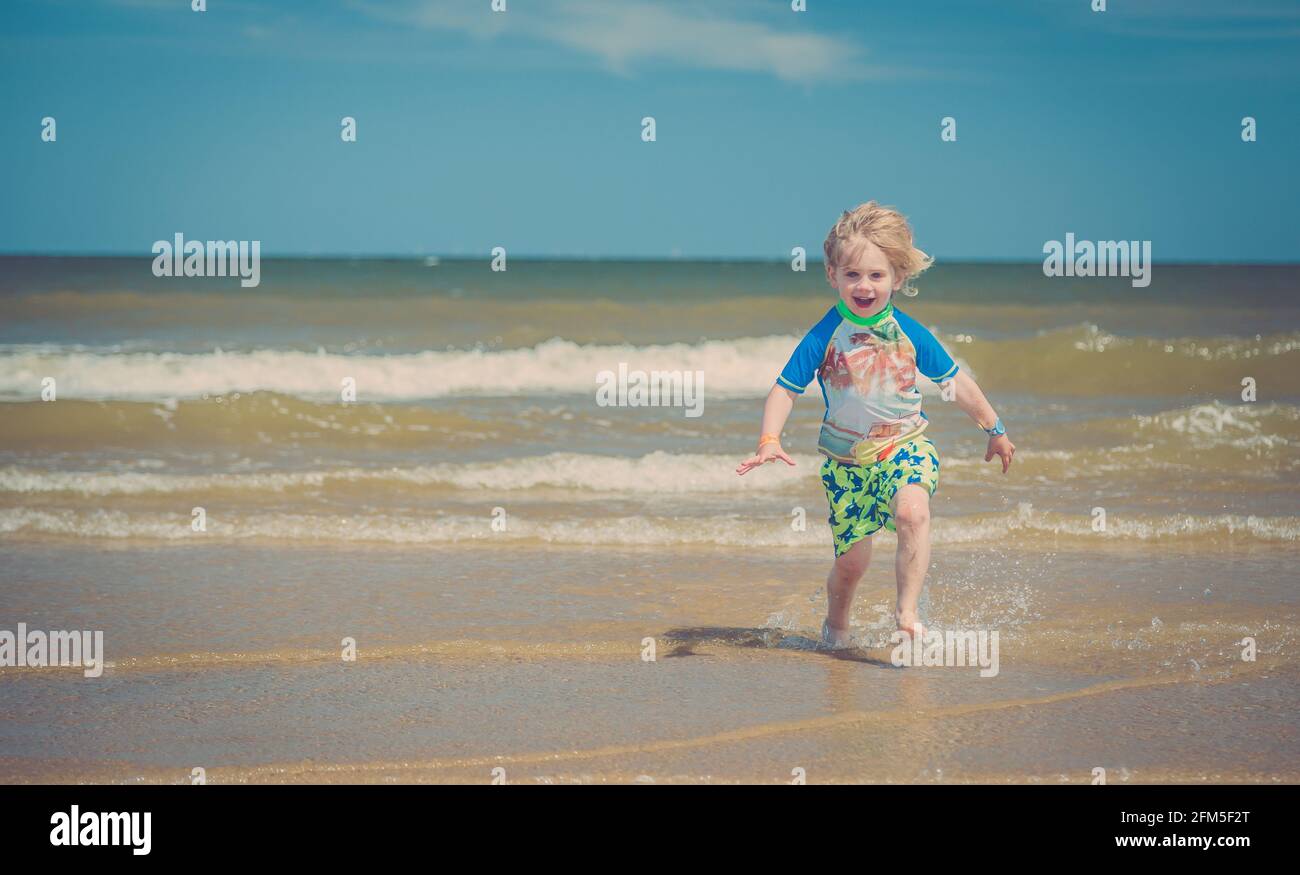 Junger blonder Haarjunge, der am Strand spielt Stockfoto