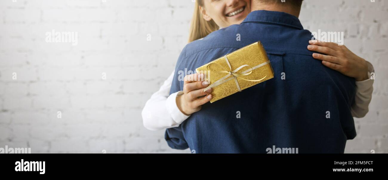 Glücklich lächelnde Frau umarmt Mann nach dem Empfang Geschenk. Geburtstag oder Jahrestag Überraschung. Copy space Stockfoto