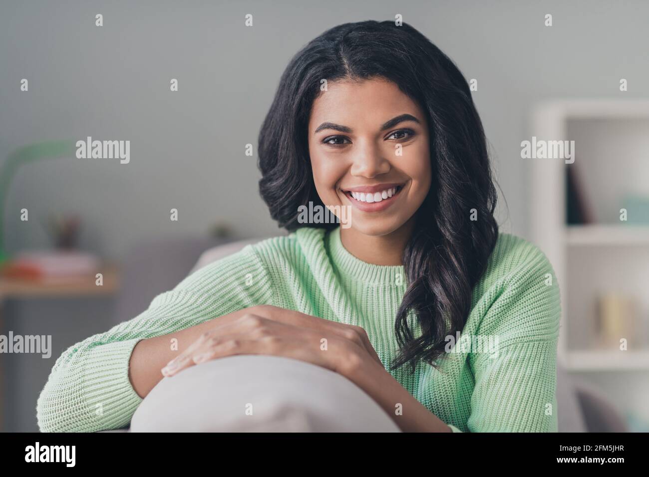 Foto von dunkler Haut charmant attraktive junge Frau tragen grün Pullover gute Laune drinnen im Apartmenthaus Stockfoto