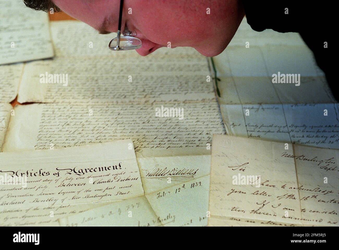 DIE BRITISCHE BIBLIOTHEK HAT KÜRZLICH EINE SAMMLUNG VON CHARLES DICKEN'S-PAPIEREN ERWORBEN. CRAIG WESTWOOD, VON DER BRITISCHEN BIBLIOTHEK, WIRD GESEHEN, WIE ER EINIGE DER DOKUMENTE UNTERSUCHT. DICKEN'S UNTERSCHRIFT ÜBER EINE VEREINBARUNG MIT SEINEM VERLAG ÜBER DIE VERÖFFENTLICHUNG VON BARNABY RUDGE LIEGT KNAPP ÜBER DEM DATUM '1839'. Stockfoto