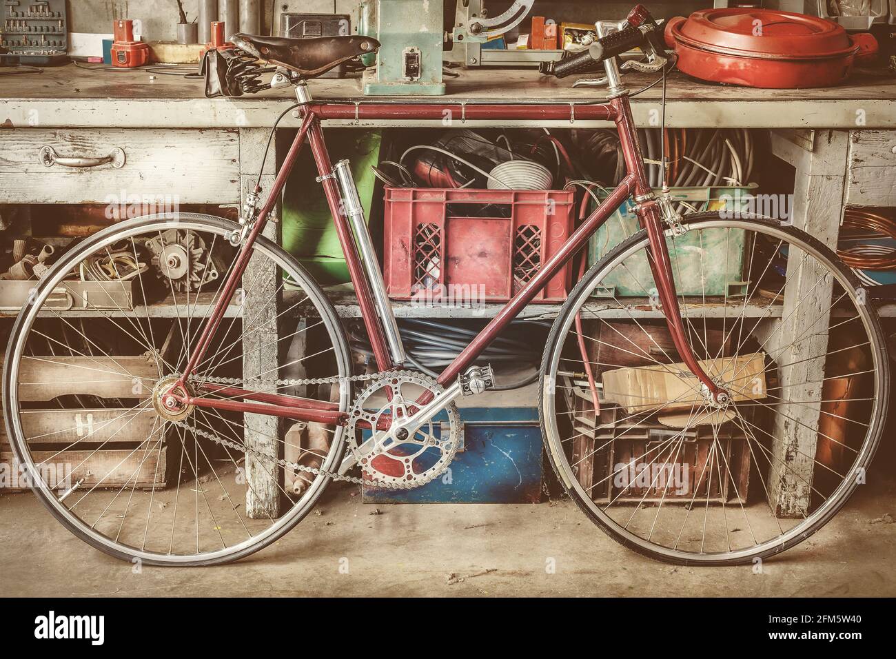 Oldtimer-Rennfahrrad vor einer alten Werkbank Mit Werkzeugen in einer Garage Stockfoto