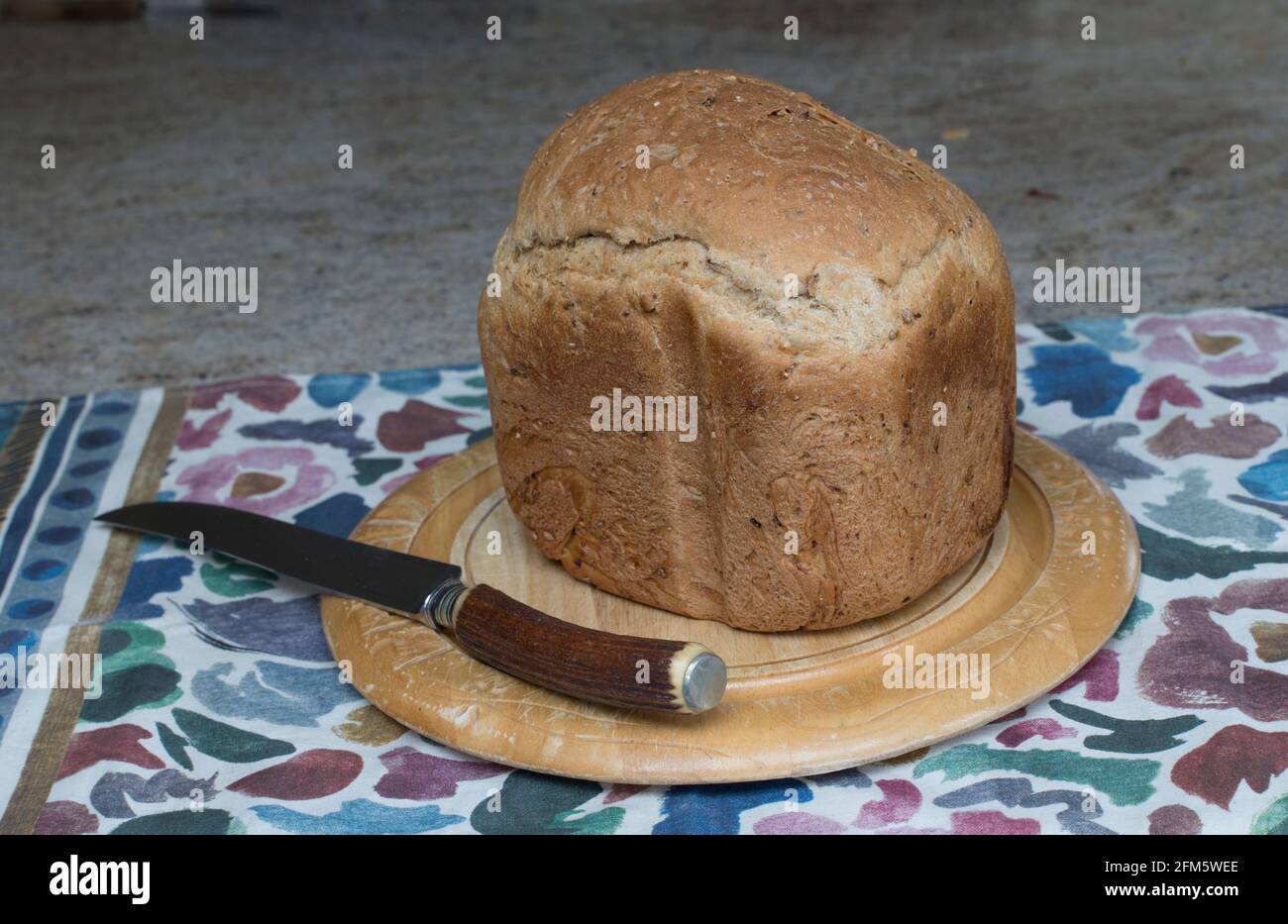 Frisch gebackener brauner Laib auf Brotbrett mit Brotmesser VEREINIGTES KÖNIGREICH Stockfoto