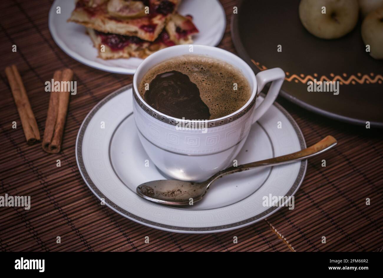 Stillleben - eine Tasse schwarzen Kaffee, hausgemachte Kekse mit Obst, gebackene Äpfel auf einer Bambusmatte Stockfoto