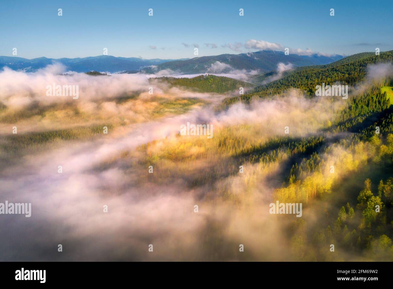 Berge in Wolken bei Sonnenaufgang im Sommer. Luftaufnahme Stockfoto