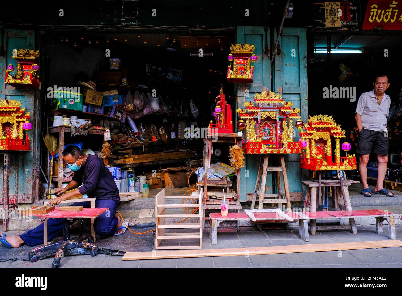 Ein Mann fertigt chinesische Themenwaren von außerhalb seiner Werkstatt in Chinatown, Bangkok, Thailand. Stockfoto