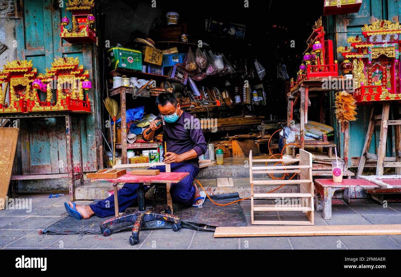 Ein Mann fertigt chinesische Themenwaren von außerhalb seiner Werkstatt in Chinatown, Bangkok, Thailand. Stockfoto
