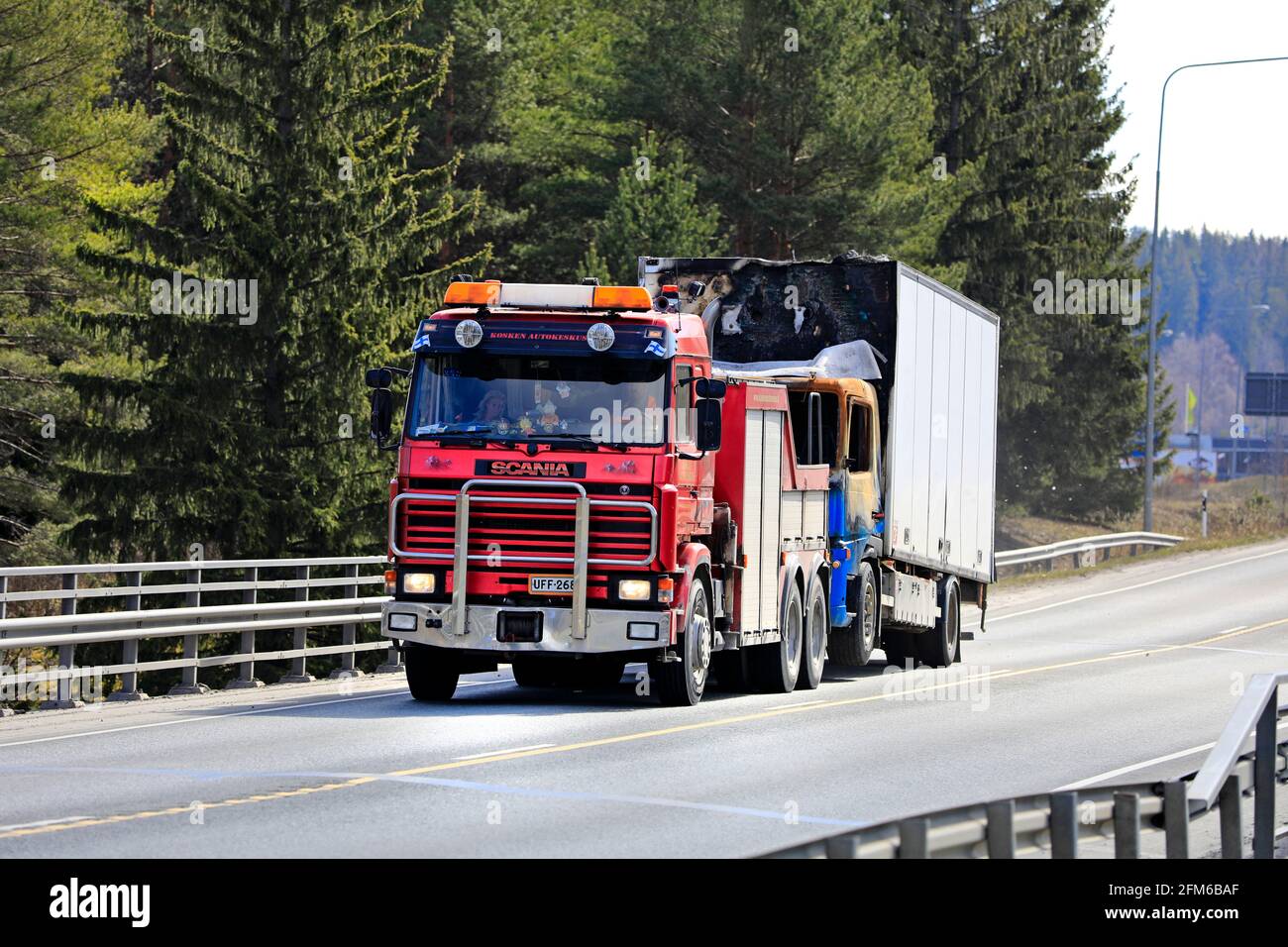 Beschädigter LKW, der von einem roten 3-Serie-Schwerlastschlepper Scania auf dem Highway 2 in Südfinnland abgeschleppt wird. Forssa, Finnland. 29. April 2021. Stockfoto