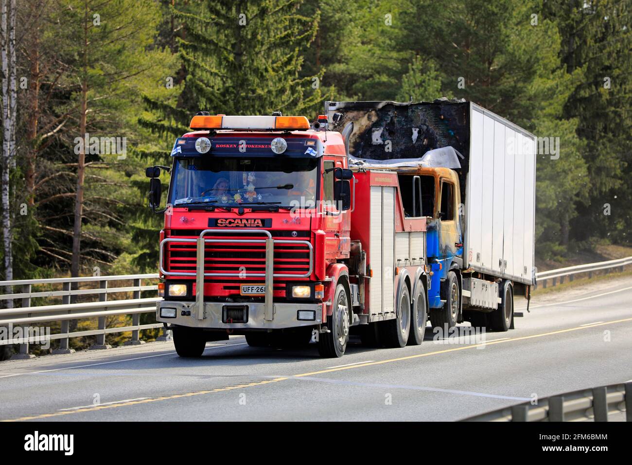 Beschädigter LKW, der von einem roten 3-Serie-Schwerlastschlepper Scania auf dem Highway 2 in Südfinnland abgeschleppt wird. Forssa, Finnland. 29. April 2021. Stockfoto
