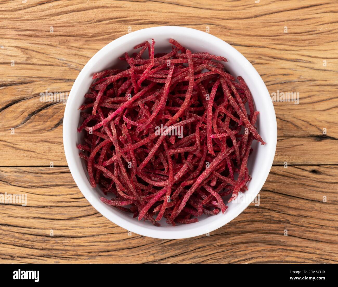 Rote Beete Streifen, im Julienne-Stil in einer Schüssel über einem Holztisch. Stockfoto