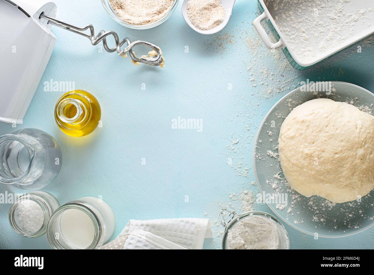 Zutaten für die Zubereitung und das Backen von hausgemachtem Brot auf blauem Tischhintergrund. Mischen und Kneten des Teigs Stockfoto