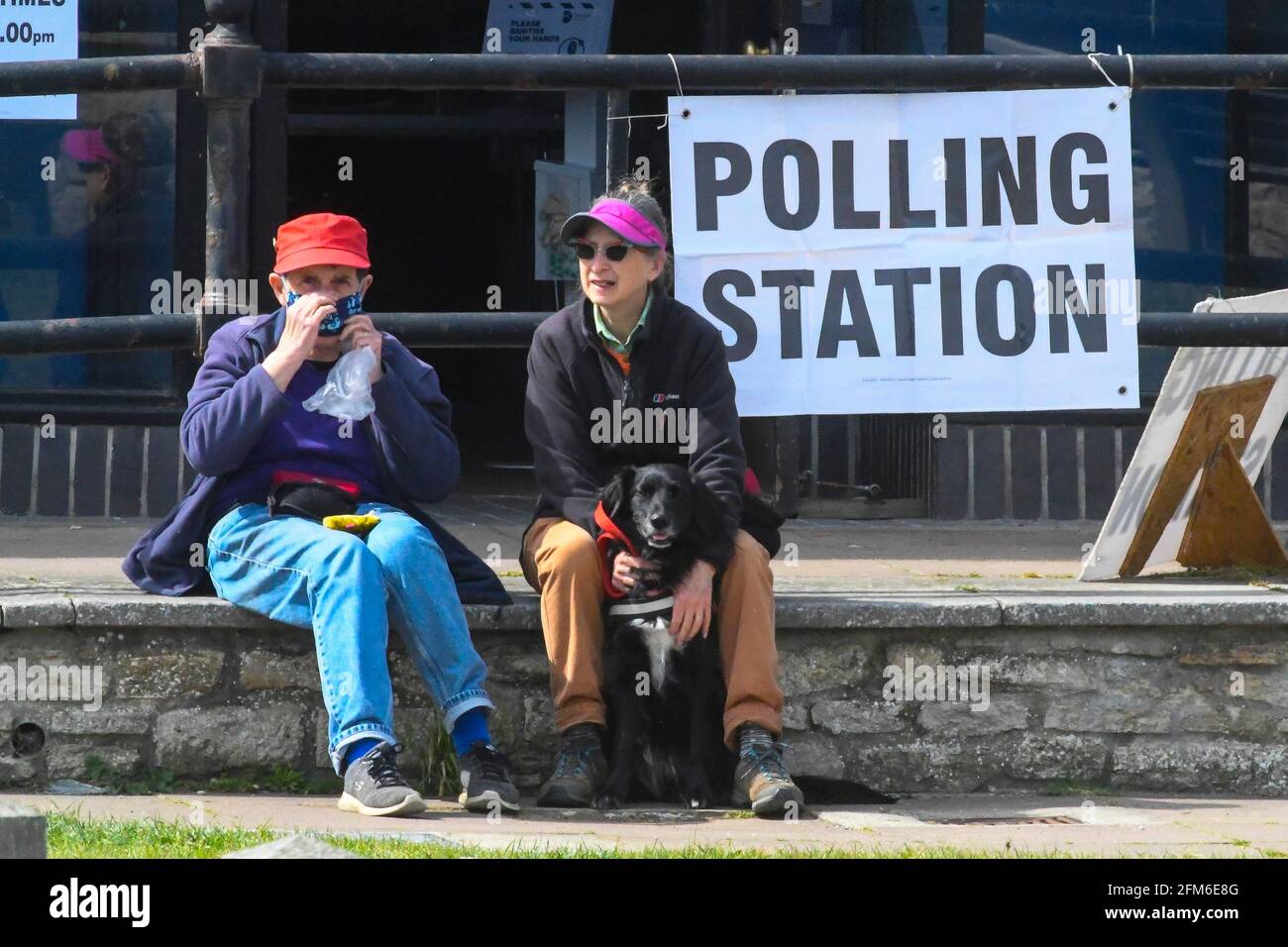 West Bay, Dorset, Großbritannien. Mai 2021. Wetter in Großbritannien. Ein Paar, das mit seinem Hund vor einem Wahllokal im Badeort West Bay in Dorset sitzt, an einem Nachmittag mit warmen Sonneneinblicken. Bildnachweis: Graham Hunt/Alamy Live News Stockfoto