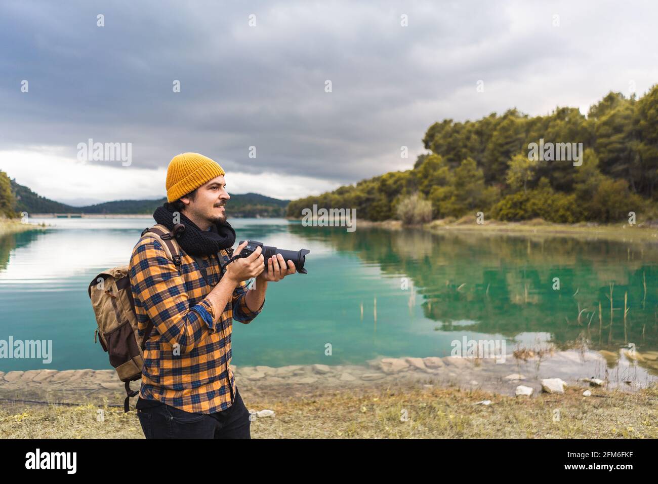 Lächelnder Tourist, der mit seiner Kamera in der Natur fotografiert Stockfoto