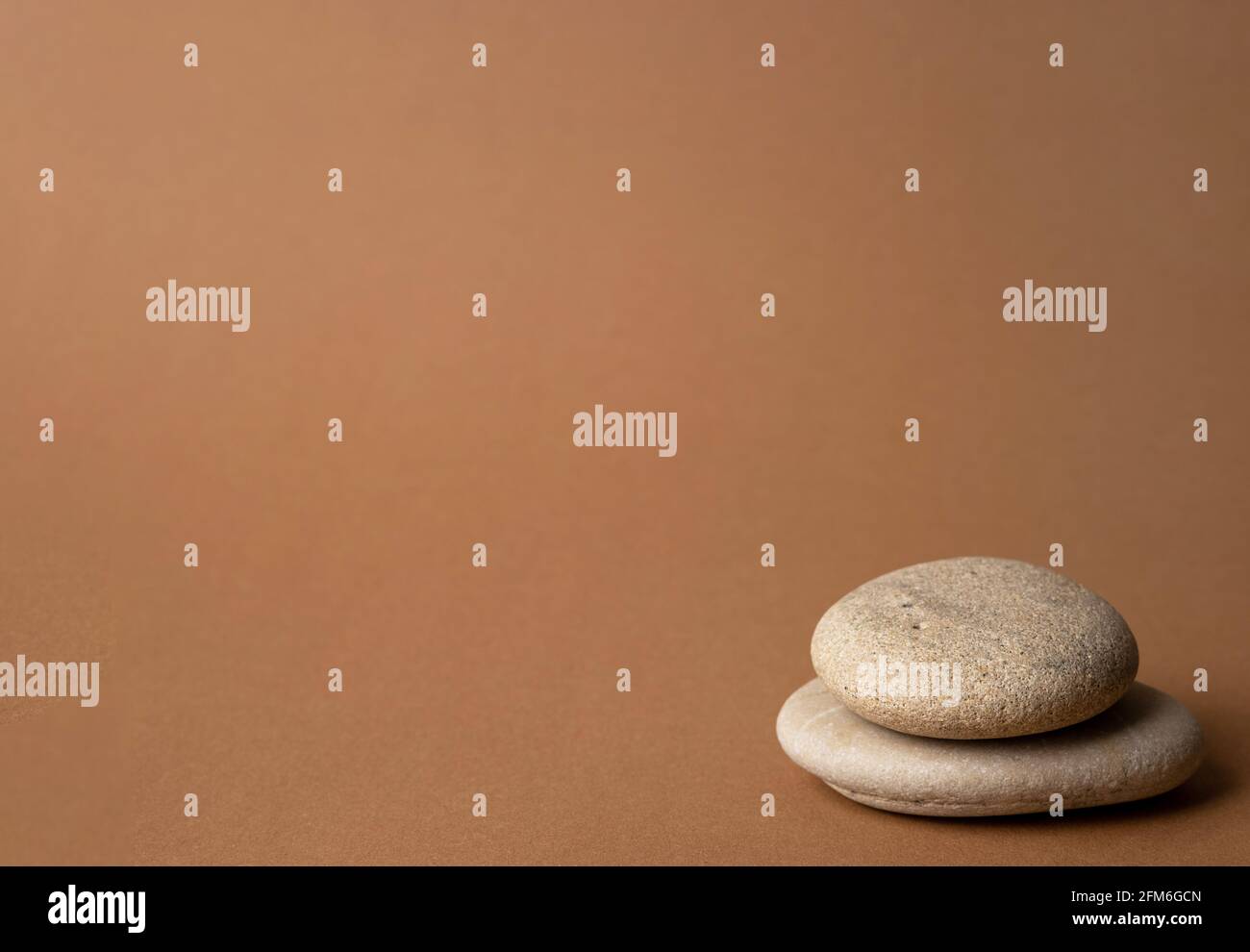 Steinkairn auf gestreiftem braunem Hintergrund, Turm aus fünf Steinen, einfache Balancesteine, Einfachheit, Harmonie und Gleichgewicht, Stein-Zen-Skulpturen Stockfoto
