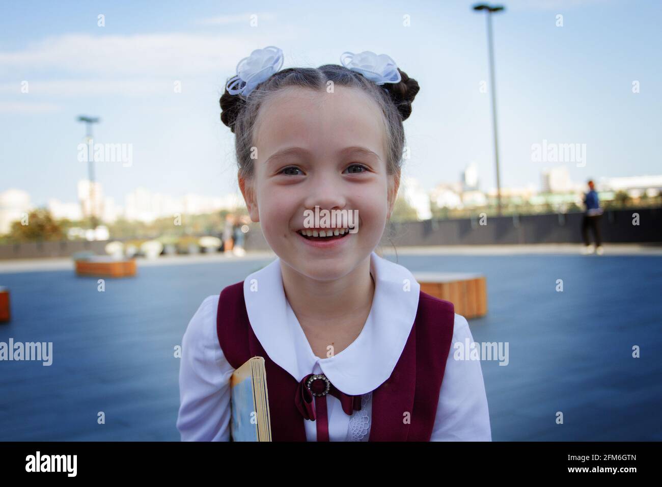 Nahaufnahme eines entzückenden kleinen Schulmädchens in stilvoller Uniform, lächelnd und lachend im Freien. Zurück zum Schulkonzept. Stockfoto