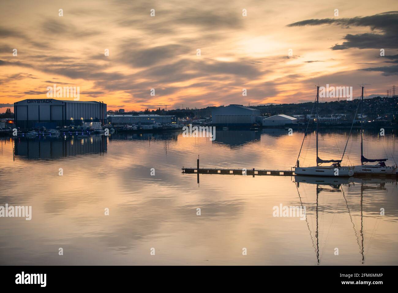 Ponton mit festgetäuten Yachten in Port Solent mit Trafalgar Wharf Werft dahinter. Sonnenuntergang. Stockfoto