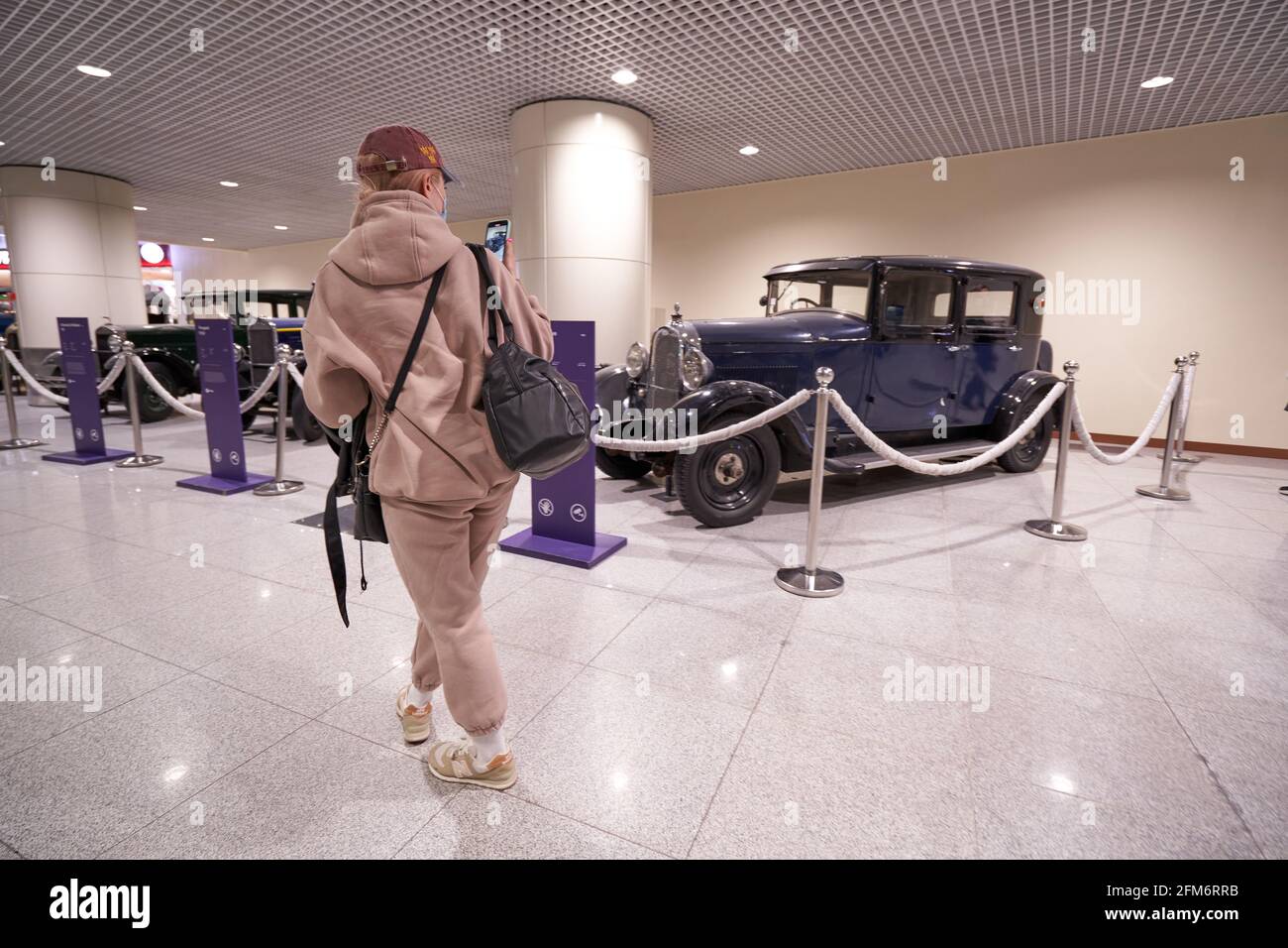 MOSKAU, RUSSLAND - 3. MAI 2021: Frau fotografiert ein Retro-Auto auf einer Ausstellung im Flughafen domodedovo Stockfoto