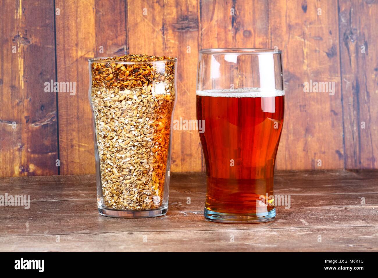 Zwei Biergläser, eines mit Craft Beer und ein anderes Mit Gerstenkorn die Rohstoffe für die Bierherstellung Stockfoto