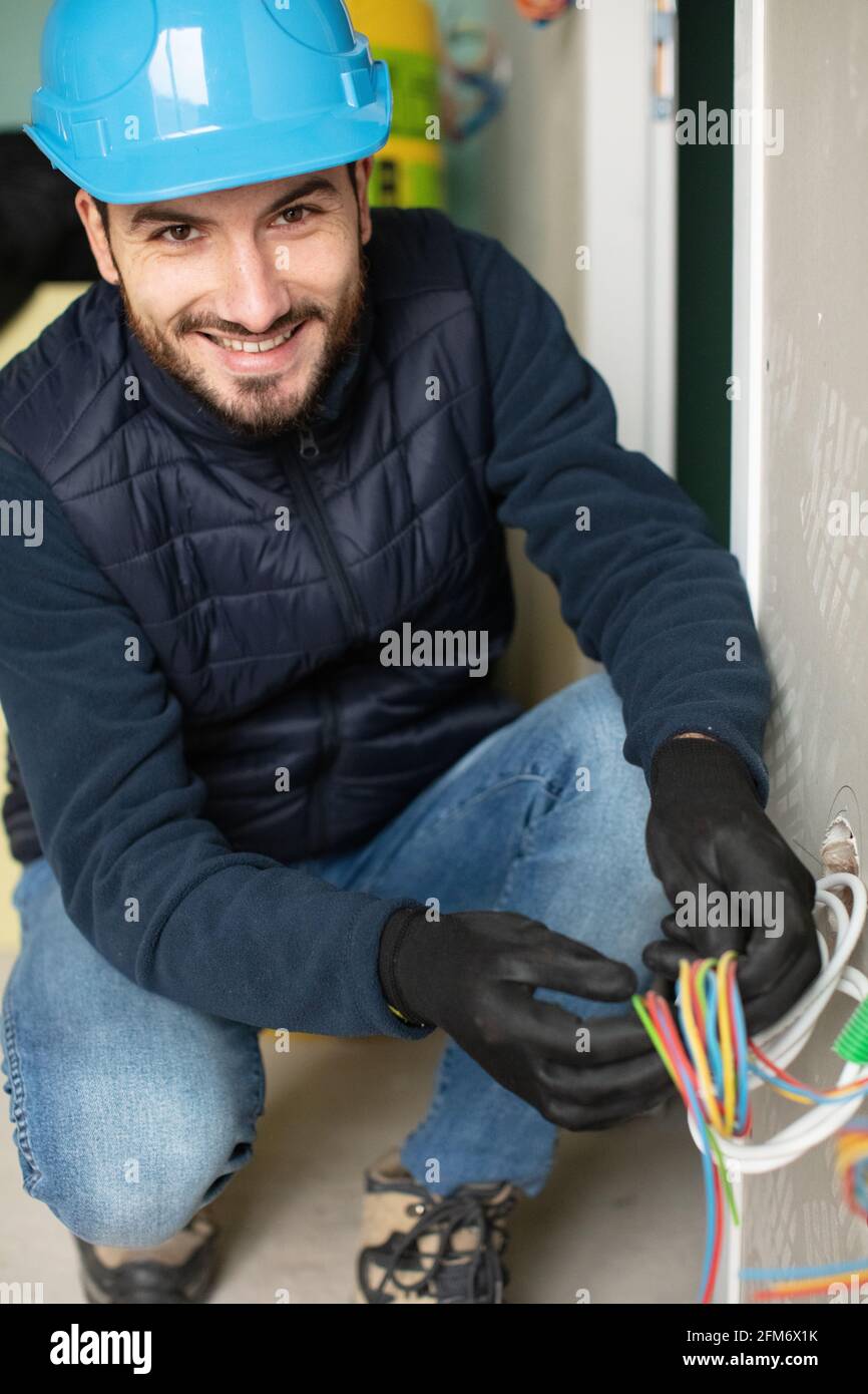 Elektriker, der Kabel an eine Steckdose in Innenräumen anführt Stockfoto