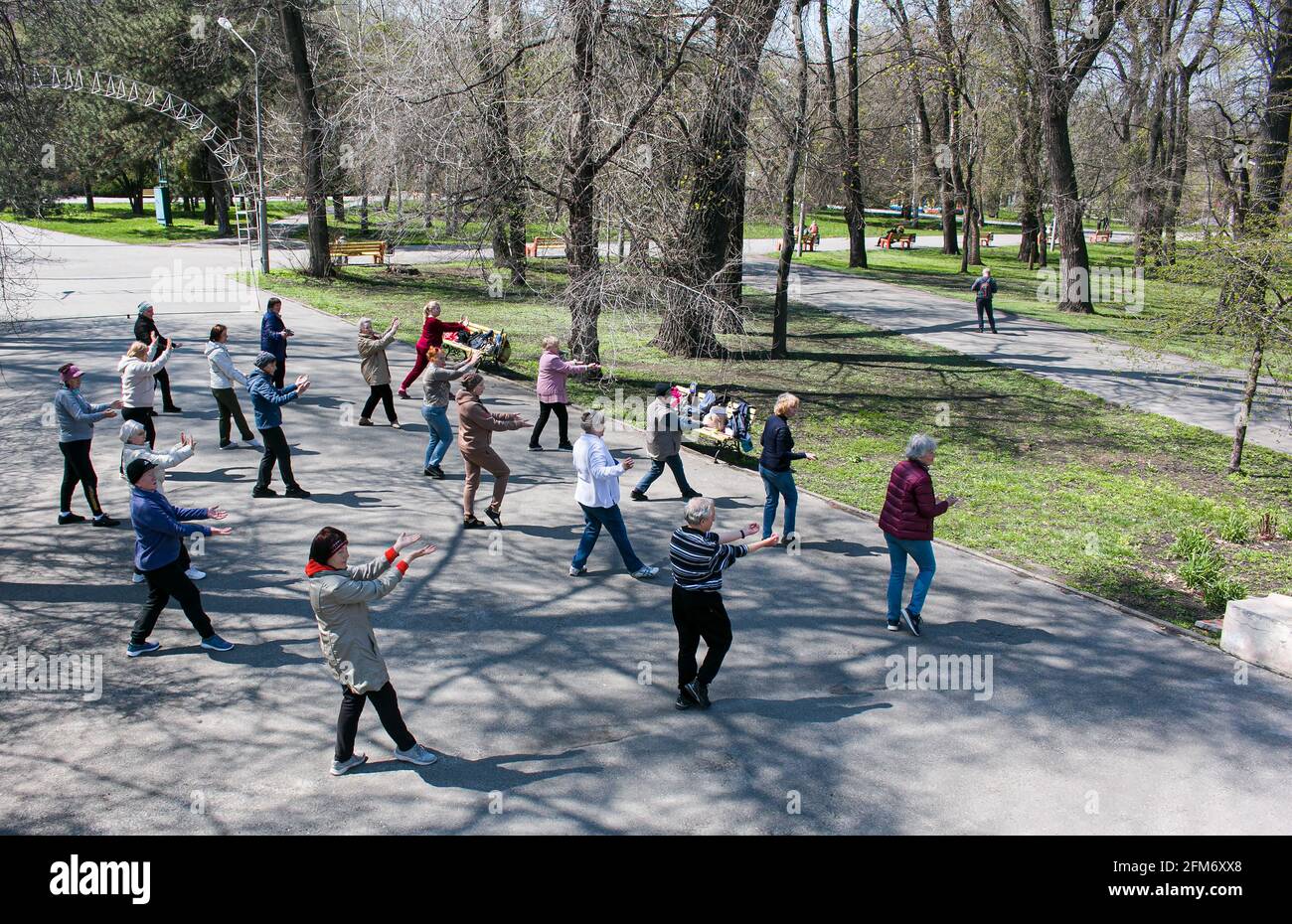 Dnepropetrovsk, Ukraine - 04.22.2021: Eine Gruppe von Senioren, die einen Gesundheits- und Fitnessgymnastikkurs in einem Park machen. Stockfoto