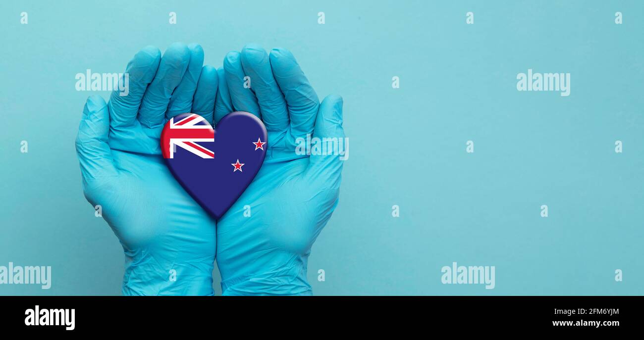 Ärzte Hände tragen chirurgische Handschuhe mit Herz der neuseeländischen Flagge Stockfoto