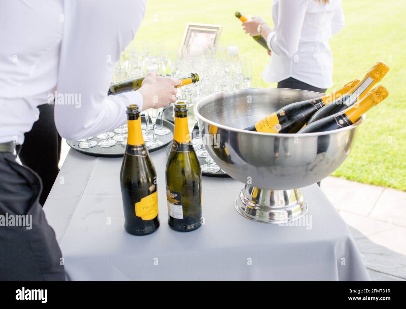 Nahaufnahme eines Kellnern, der neben und einen Prosecco ausschüttete Eiskübel mit Prosecco-Flaschen Stockfoto
