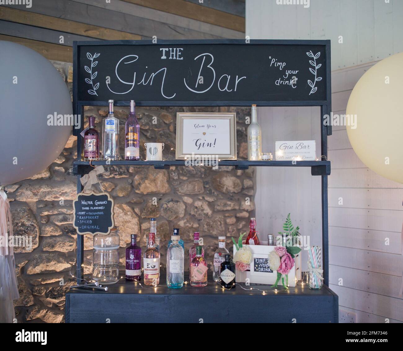 Eine Gin Bar mit vielen bunten Flaschen Gin vor einer Steinmauer bei einer Party, Veranstaltung oder Hochzeit Stockfoto