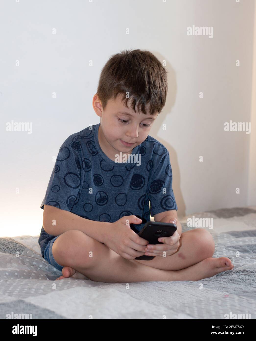 Kind Junge spielt mit einem Smartphone mit weißem Hintergrund Stockfoto