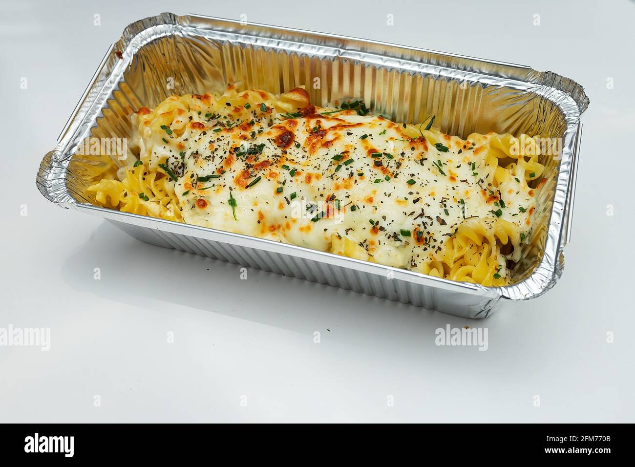 Heiße italienische Makkaroni in einem Einweggericht zur Lebensmittelzustellung, kalorienreiche Fast-Food-Pasta auf weißem Hintergrund Stockfoto