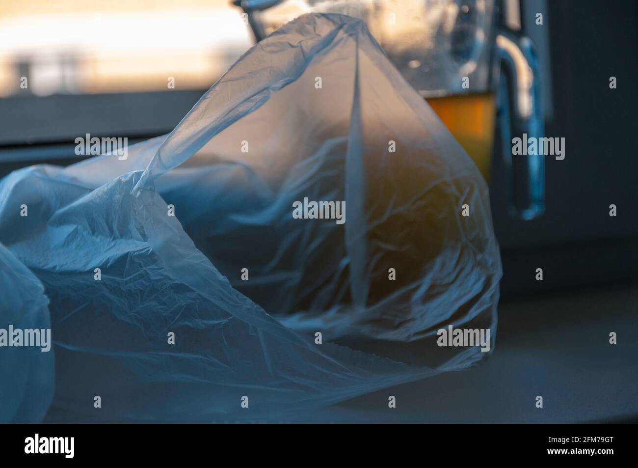 Leeren Sie den Plastikbeutel. Konzept von Kälte und Leerheit. Blaues kaltes Licht in einem Raum. Kanne auf der Fensterbank Stockfoto