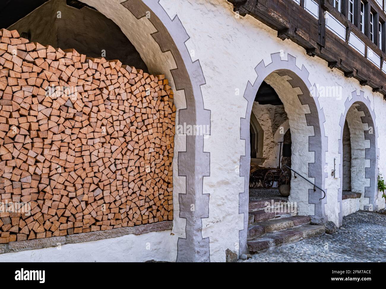 Ein Stapel Brennholz unter dem Bogen des traditionellen mittelalterlichen Hauses Werdenberg, Schweiz Stockfoto