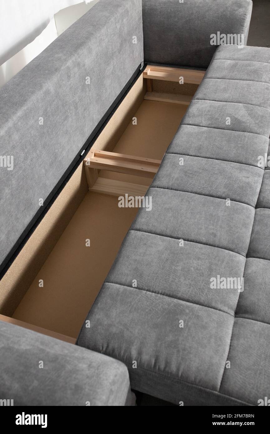 Vertikale Aufnahme einer grauen, drapierten Couch, die sich in verwandelt Ein Bett Stockfoto