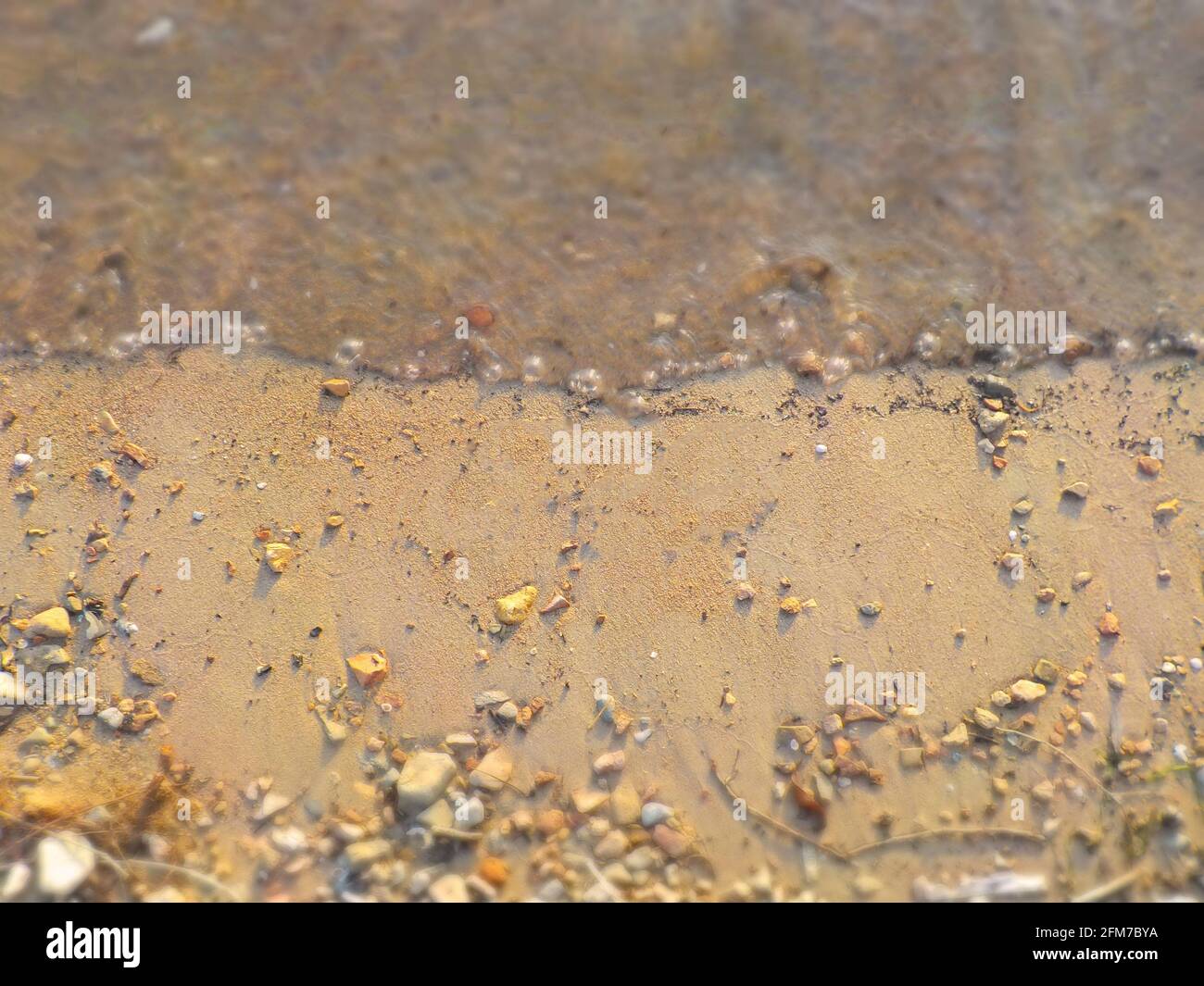 Wellen, Felsen, Sand mit Fokus auf das Zentrum als natürlicher Hintergrund. Stockfoto