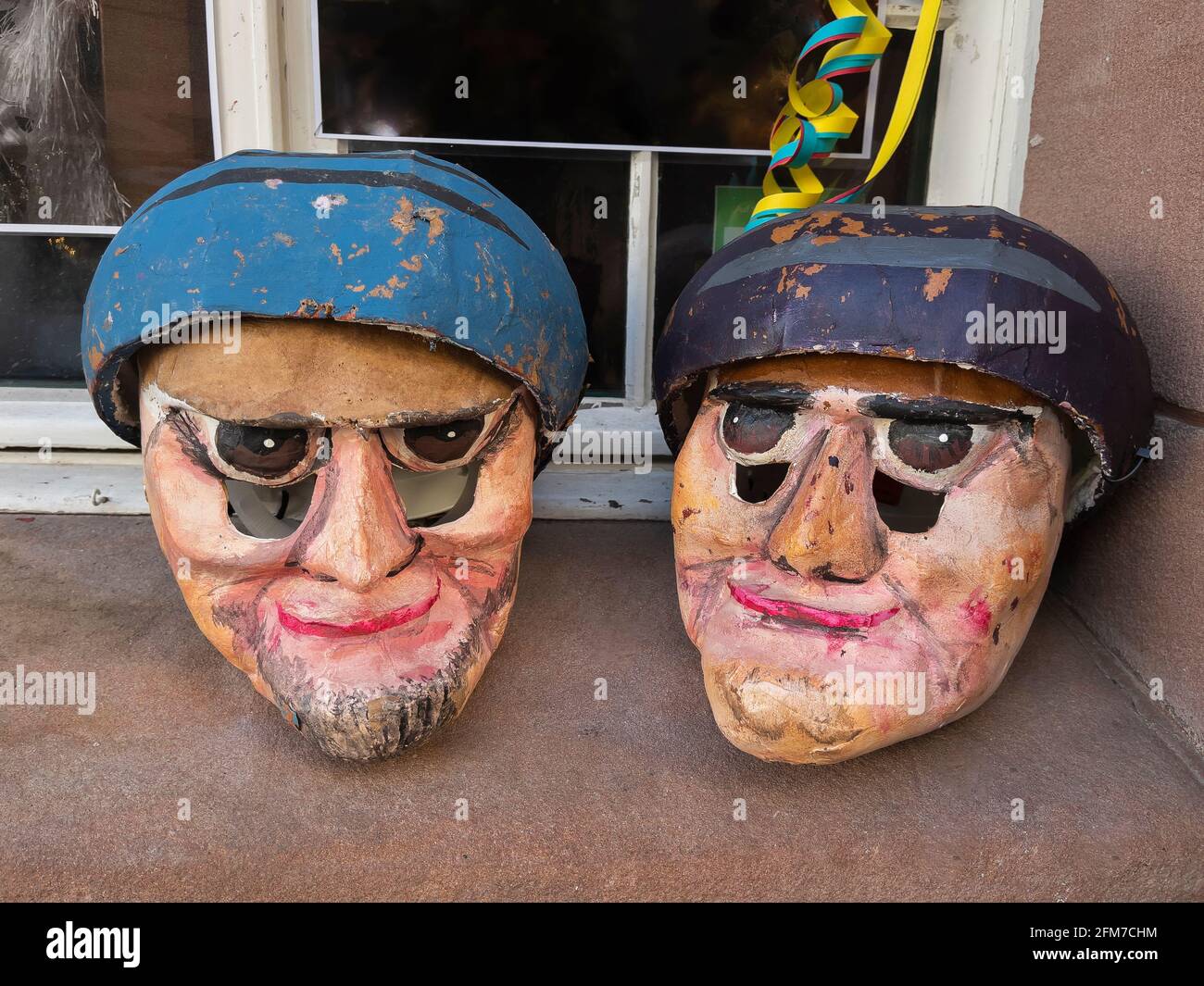 Zwei selbstgemachte Karnevalsmasken auf einer Fensterbank vor einem Haus in Basel, Schweiz Stockfoto