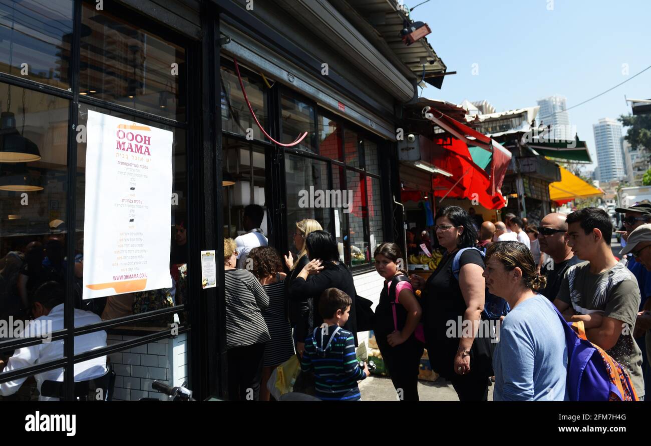 Eine lange Schlange von Menschen, die darauf warten, in den OOOH Mama-Laden mit hausgemachten Lebensmitteln auf dem Carmel-Markt in Tel-Aviv, Israel, zu kommen. Stockfoto