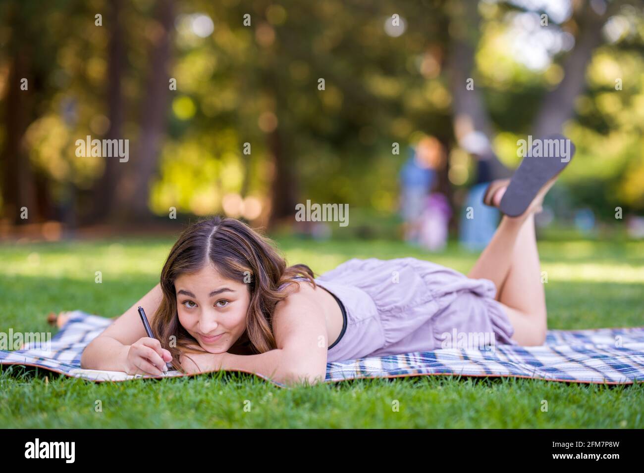 Petite junge asiatische Frau Student schreiben im Park Stockfoto