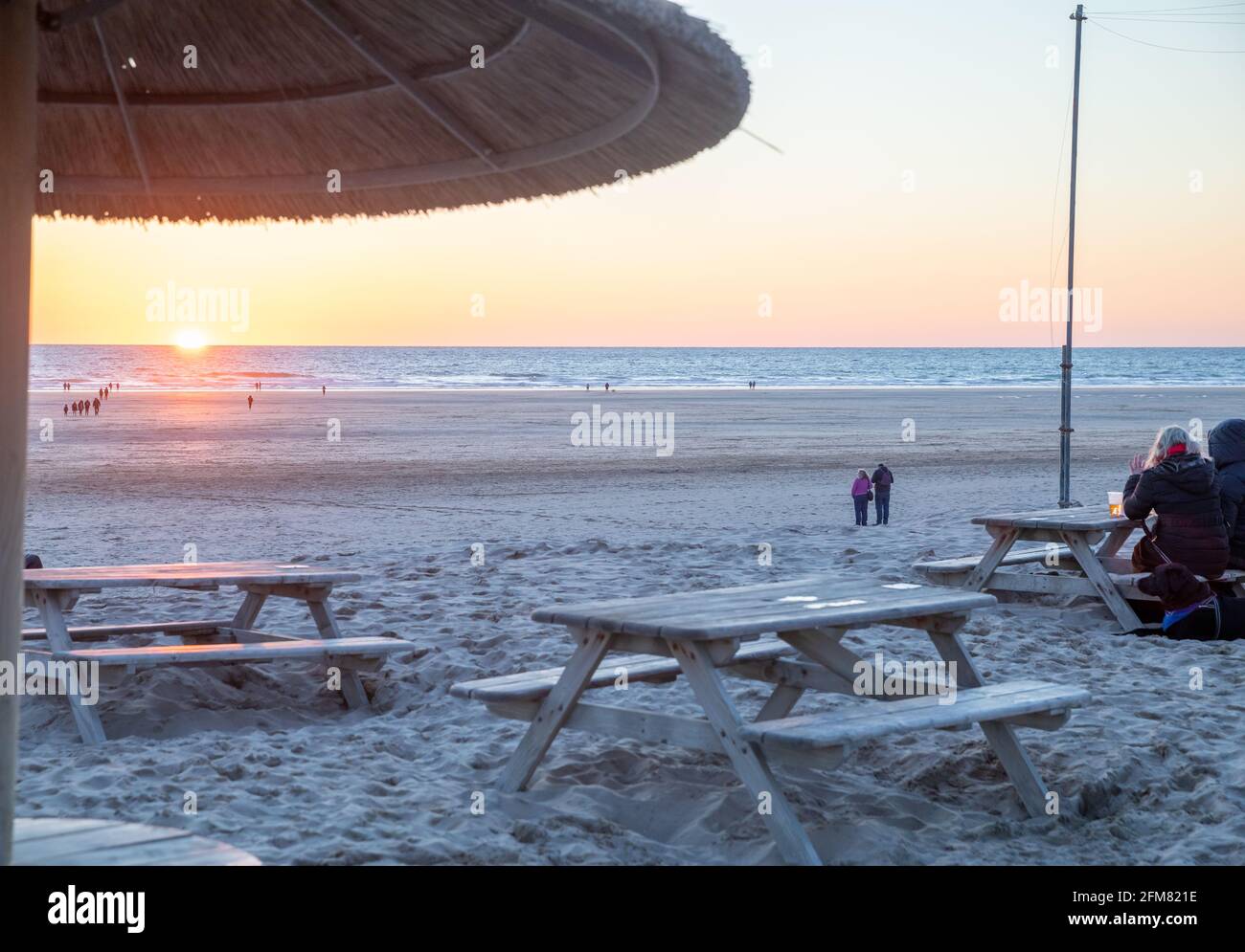 Die Leute stehen am Strand, um den Sonnenuntergang über dem Perranporth Beach in Cornwall, Großbritannien, zu beobachten Stockfoto