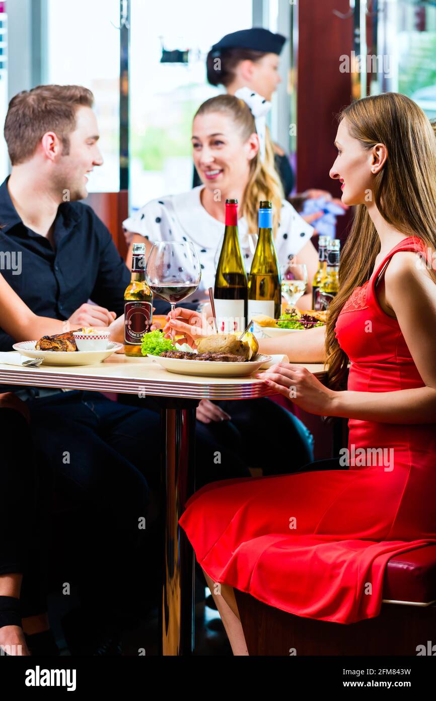 Freunde oder Paare Fast-Food Essen und trinken Bier und Wein in einem amerikanischen Fast-Food-Imbiss Stockfoto