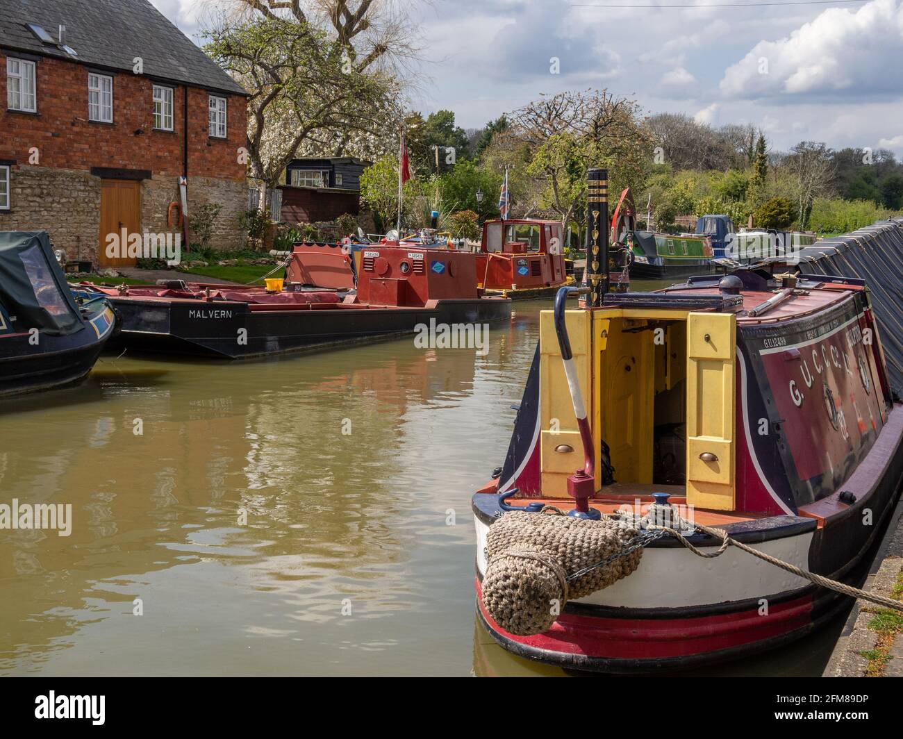 Narrowboats vertäuten im Frühjahr auf dem Grand Union Kanal in Stoke Bruerne, Northamptonshire, Großbritannien Stockfoto