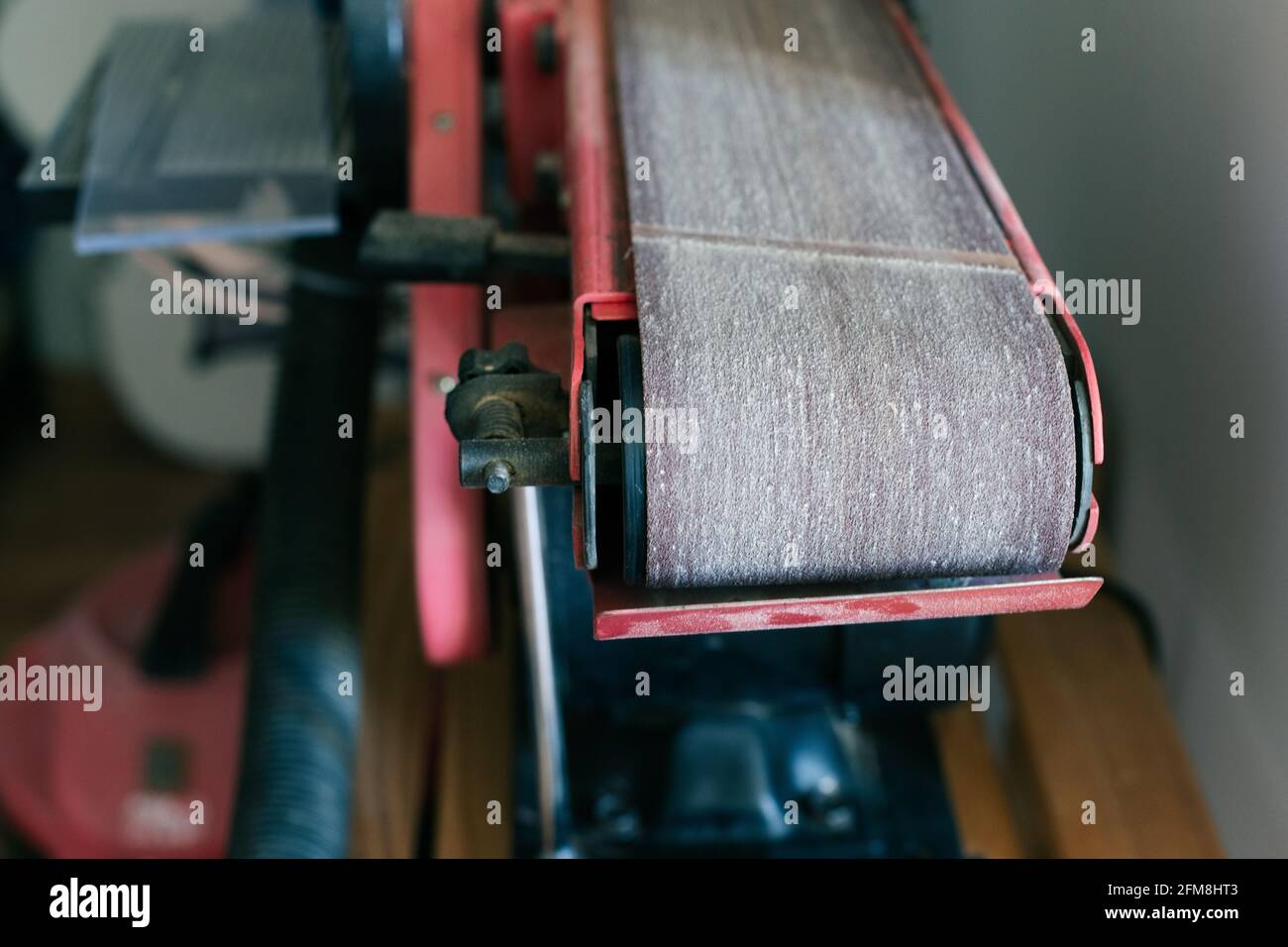 Nahaufnahme eines gebrauchten Bandschleifers in einer Geigenbauwerkstatt Stockfoto