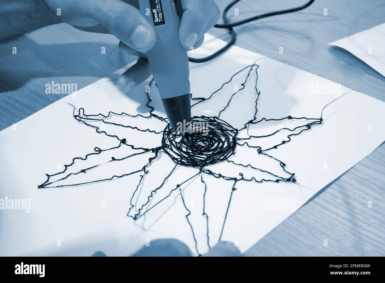 Man 3d Pen zeichnet eine Blume auf weißes Papier Stockfoto