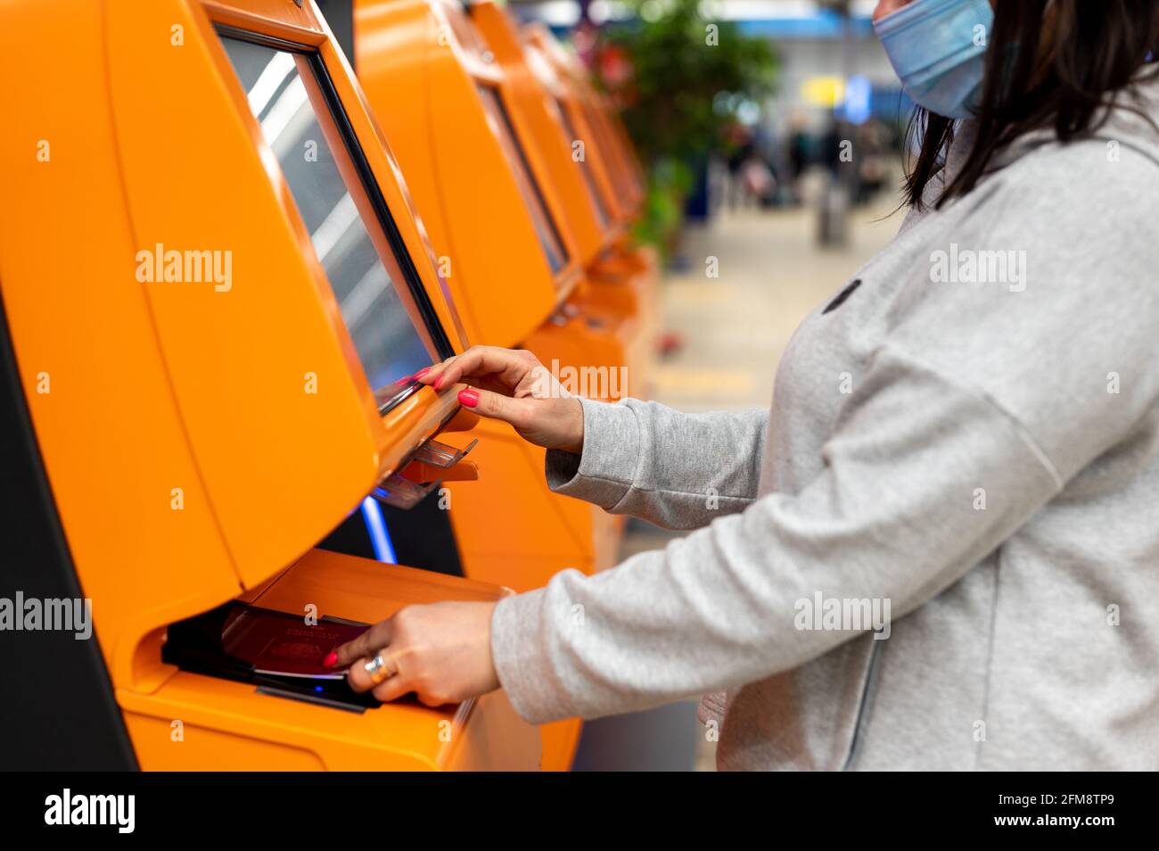 Frau scannt ihren Reisepass am Schalter der Fluggesellschaft für den Self-Check-in am Flughafen. Frau macht die Selbstregistrierung für den Flug. Automat mit Selbstbedienung Stockfoto