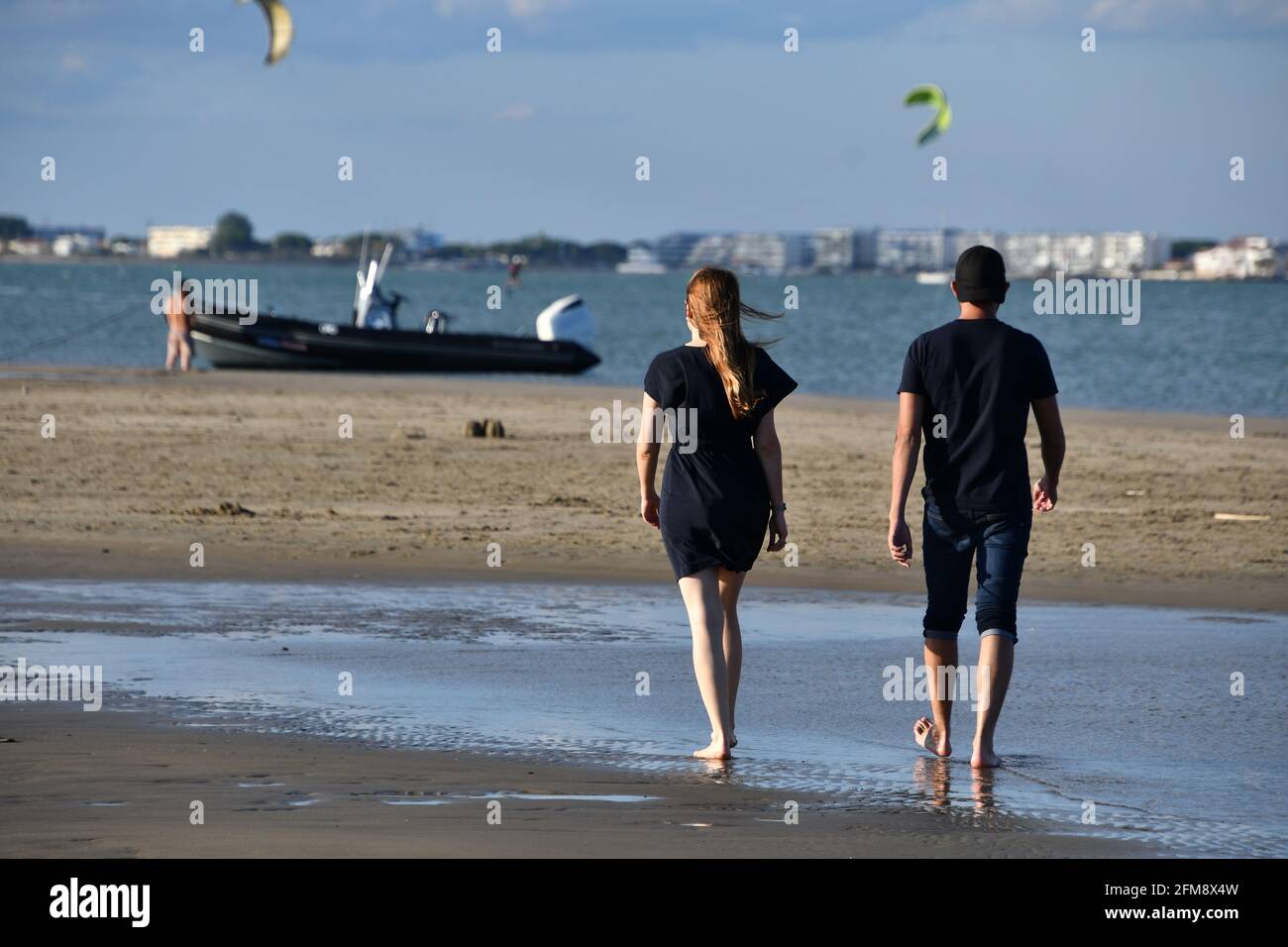 Junges Paar, das am Strand am Sandufer in Port Camargue, in der Nähe von La Grande Motte und Montpellier, in der Nähe von Uppsland, Südfrankreich, spazieren geht Stockfoto