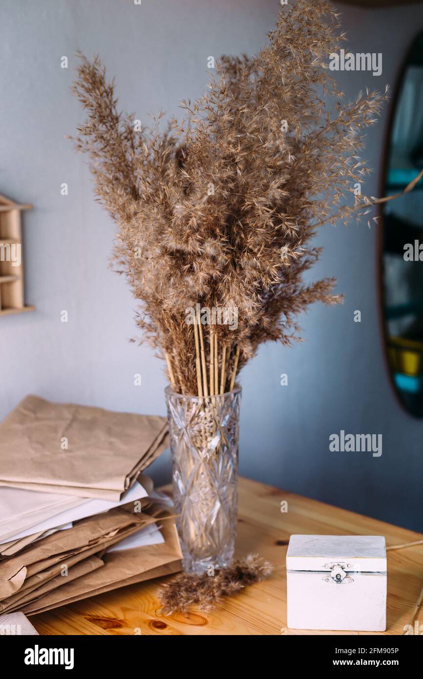 Trockenes Schilf, Schilf in Vase, Bastelpapier, Holz und neutrale Farben im Stillleben Stockfoto